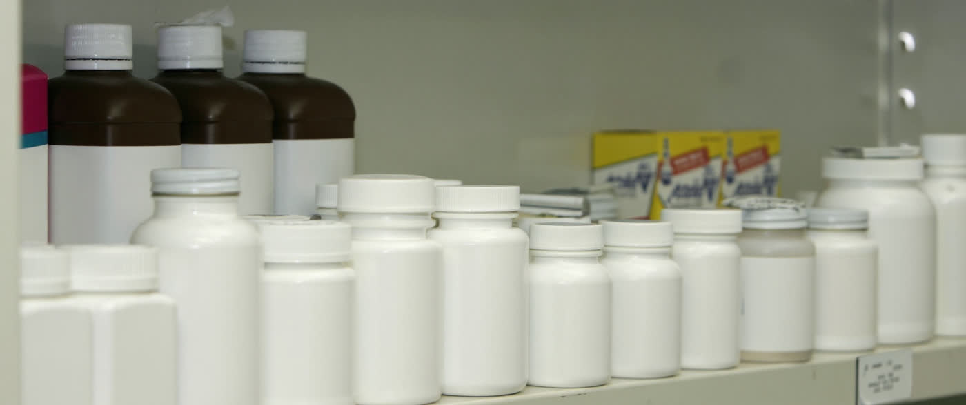 Pharmacy shelves lined with plain white medication bottles