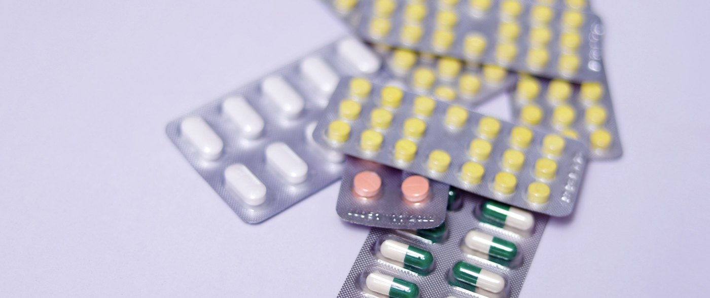 Assorted blister packs of tablets and capsules on a plain surface